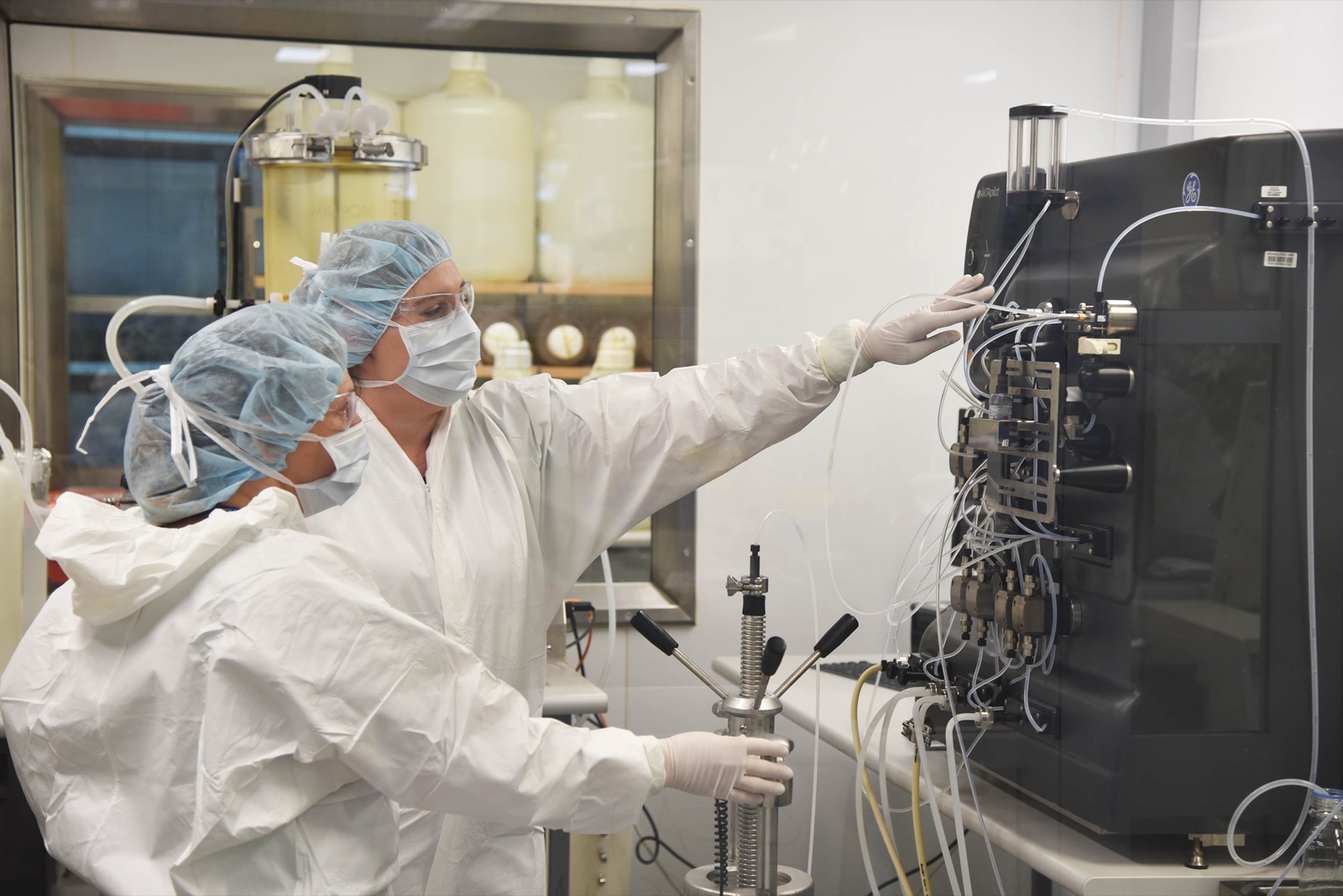 Gowned operators at a chromatography purification skid during clinical-grade manufacturing